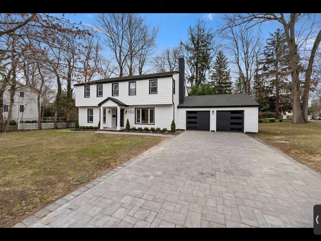 Renovated colonial home exterior with paver driveway