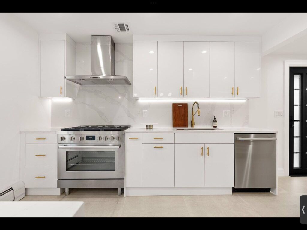 Modern white kitchen with brass hardware and marble backsplash